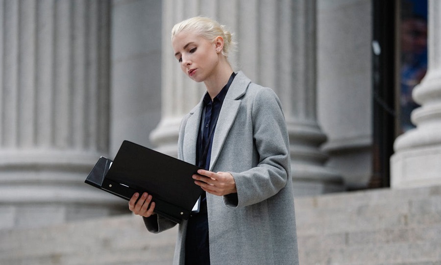 contemplative-businesswoman-reading-papiers-dans-le-dossier-a-l-exterieur-du-batiment